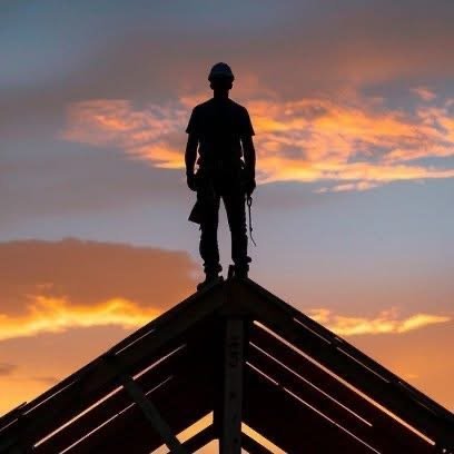 Silhouette standing on a roof peak at sunset